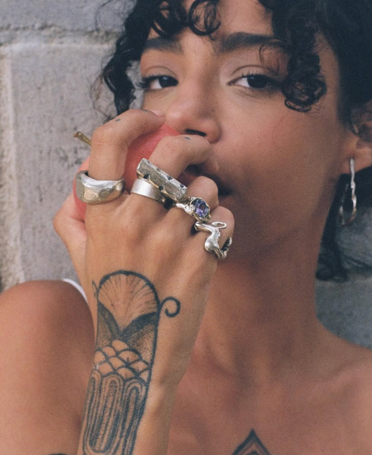 Primer plano editorial de una modelo con tatuajes y anillos.