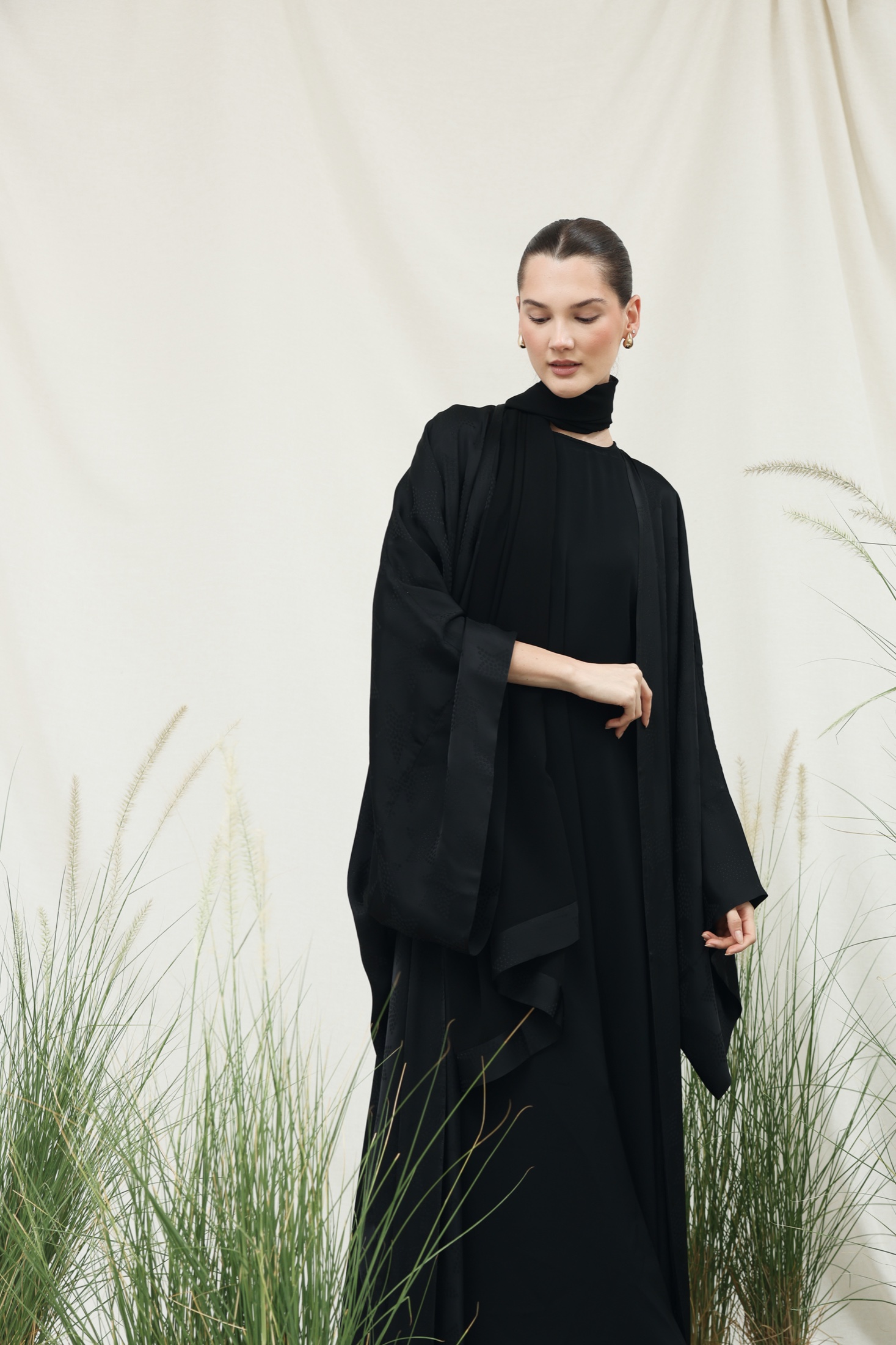 Model in a black abaya among grasses.