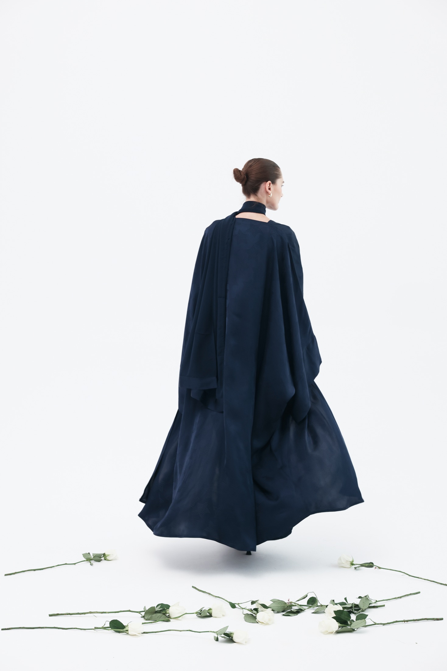 Navy abaya in motion among white flowers.
