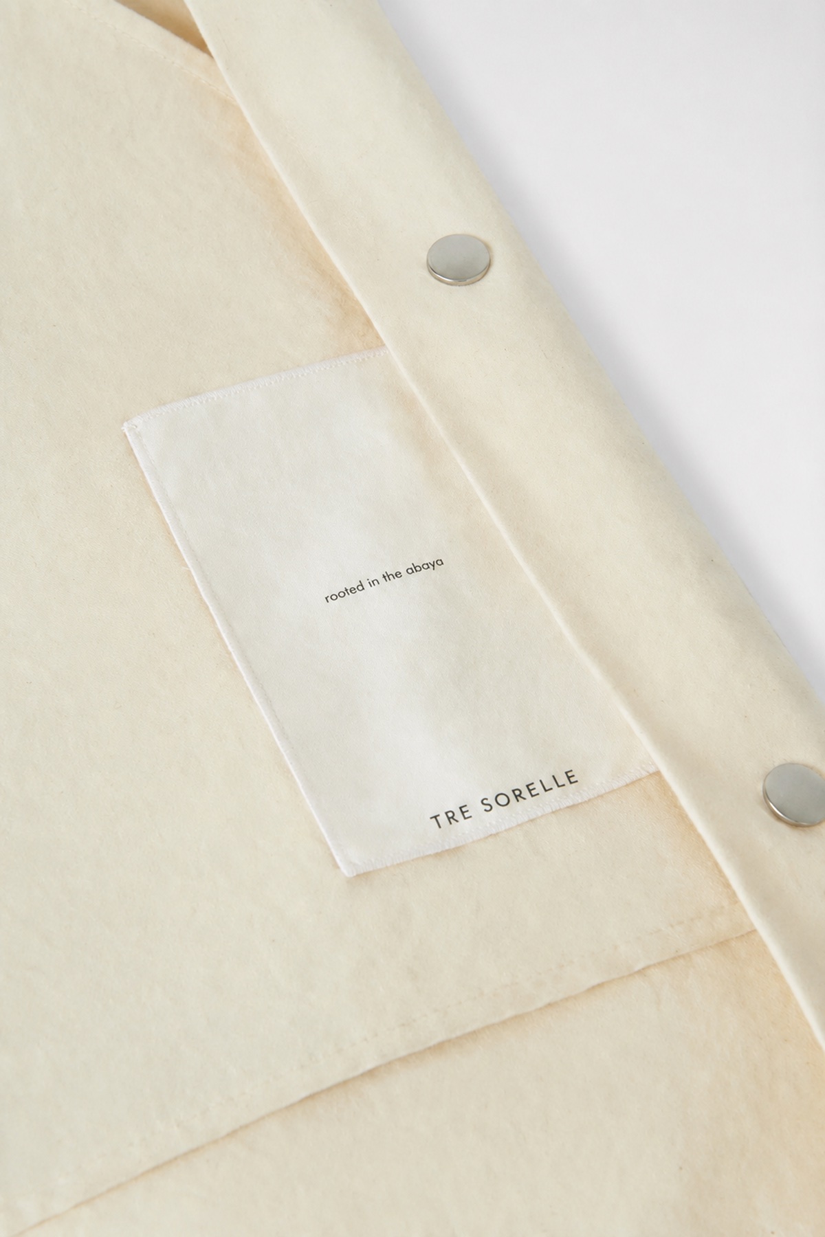 Tre Sorelle garment tag placed on cream fabric.